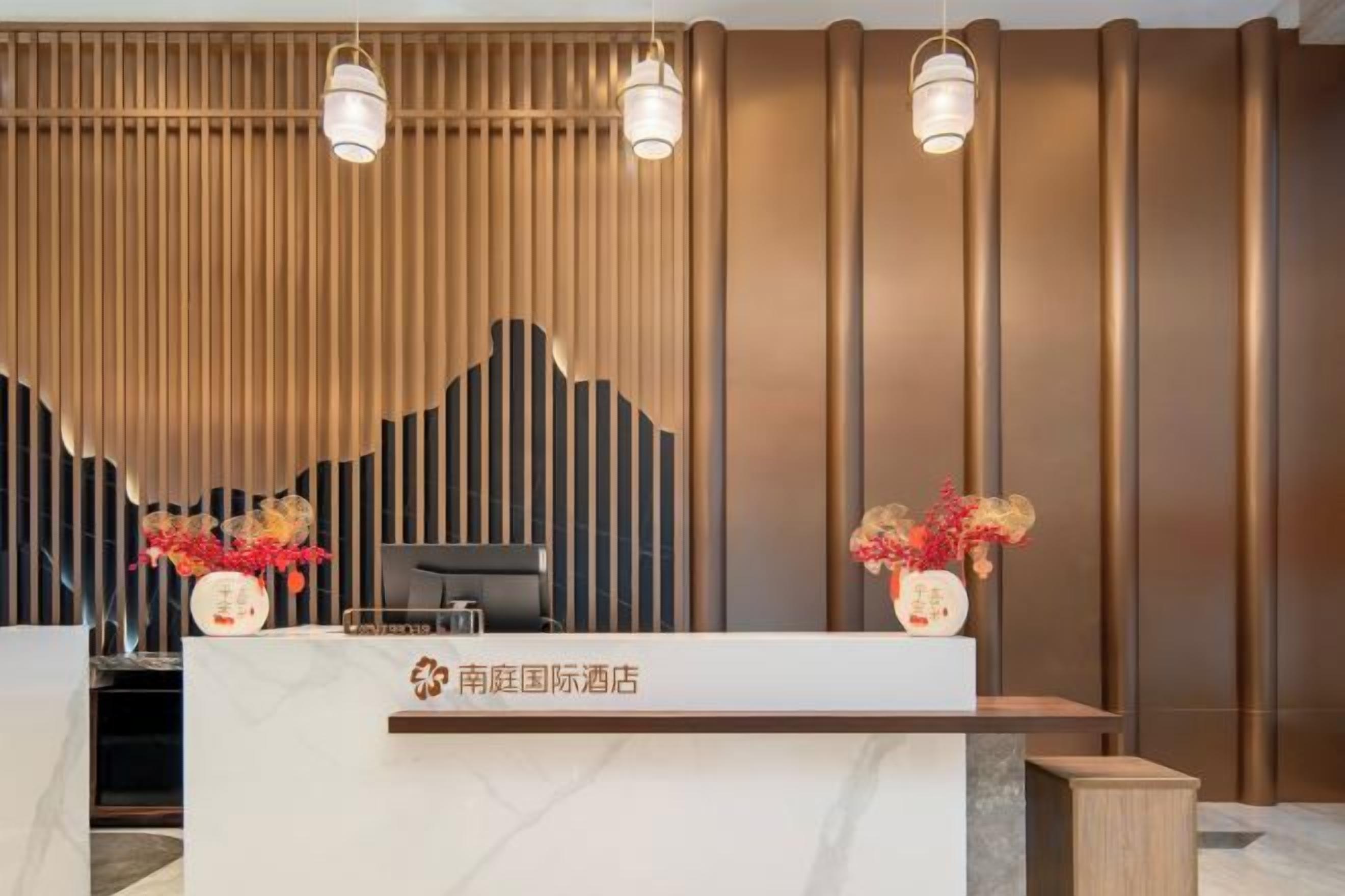 Un comptoir d’accueil au design moderne, un mur avec des panneaux verticaux et deux luminaires suspendus.