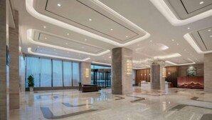 Un lobby amplio con una recepción, ventanas grandes y un diseño de techo moderno.