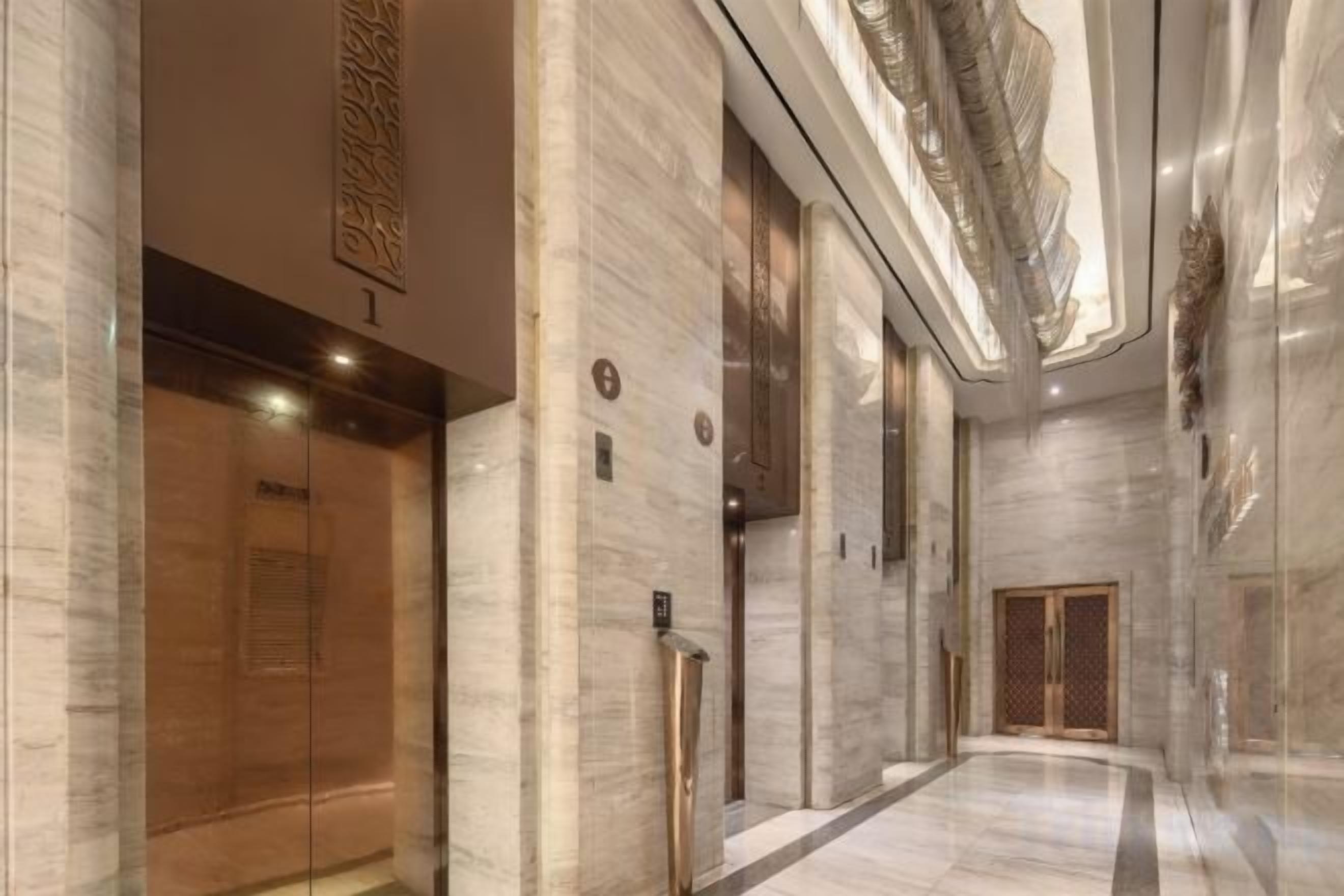 A corridor with marble walls, a wooden elevator, and a glass door.