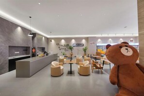 Un lobby moderno con un mostrador de recepción, zona de estar y una gran decoración con un oso de peluche.