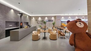 Un vestíbulo moderno con mostrador de recepción, zona de estar y una gran estatua de un osito de peluche.