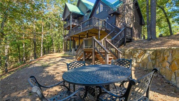 A rustic cabin with a balcony and stairs leading to the entrance, surrounded by trees. - Beautiful Paradise Ridge, Broken Bow Cabin with Hot Tub (Broken Bow)