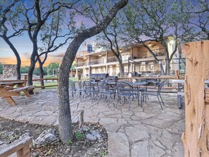 Un espacio al aire libre con patio, suelo de piedra, sillas de metal y una parrilla de barbacoa.