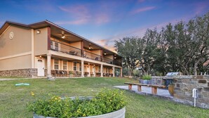 A two-story building with a covered patio area, outdoor seating, and a stone wall with a grill. - Private Lakeview Resort/Sleeps up to 25/Pet Friendly/Walking Distance to Lake (Canyon Lake)