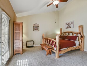 Un dormitorio con una cama y un banco de madera, un armario y un ventilador de techo.