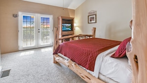 A bedroom with a large bed, a ceiling fan, a TV, and a door leading to a balcony. - Private Lakeview Resort/Sleeps up to 25/Pet Friendly/Walking Distance to Lake (Canyon Lake)