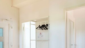 Une pièce avec un plancher en bois, des murs blancs et une armoire blanche équipée d’une tringle pour suspendre les vêtements.