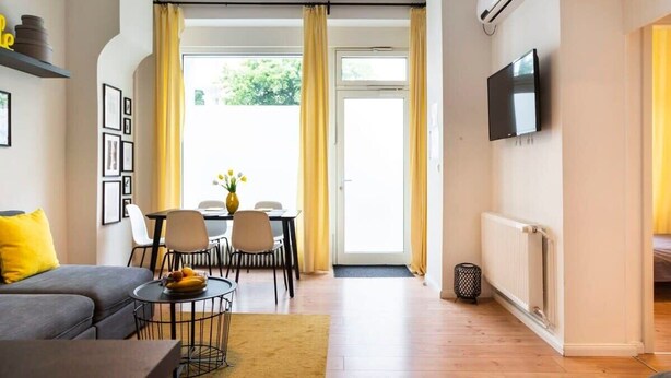 Ein modernes Wohnzimmer mit einer Couch, einem Esstisch, Stühlen und einem Fernseher.