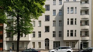 Ein mehrstöckiges Gebäude mit einer symmetrischen Fassade, großen Fenstern und Balkonen.
