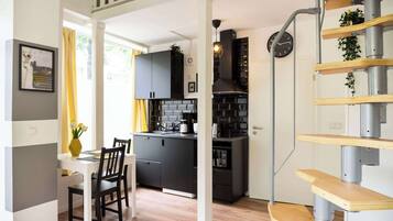 A modern kitchen with black cabinets, a wooden dining table, and a staircase with wooden steps.