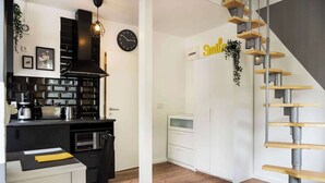 A modern kitchen with a black and white color scheme, a staircase with wooden steps, and a wall-mounted clock. - Charmante Wohnung in Berlin-Wilmersdorf (Berlin)