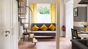A modern living room with a sofa, yellow cushions, a staircase, and a dining area. - Charmante Wohnung in Berlin-Wilmersdorf (Berlin)