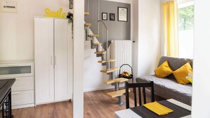 A modern living space with a staircase, a sofa with yellow cushions, a dining table, and a cabinet. - Charmante Wohnung in Berlin-Wilmersdorf (Berlin)