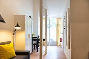 Een hal met een bank, een lamp, een eettafel met stoelen en een brandblusser.