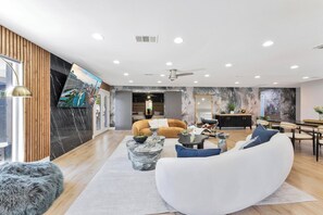 A modern living room with a sofa, coffee table, and a dining area. - ❤️Luxury Villa 4BR 4 BA with pool mins from strip (Las Vegas)