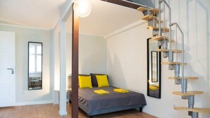 A bedroom with a bed, a wooden floor, a staircase, and a window. - Stylish Loft Apartment (Berlin)