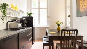 A modern kitchen with a built-in oven, a sink, and a dining area with a wooden table and chairs. - Stylish Loft Apartment (Berlin)