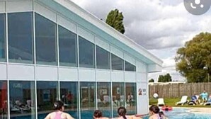 A swimming pool area with a glass building in the background.