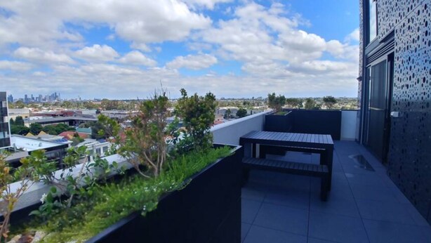 A rooftop terrace with a view of a city skyline, a small table, and a seating area. - New Spacious 2 Bedroom With Gorgeous City Views (Northcote)