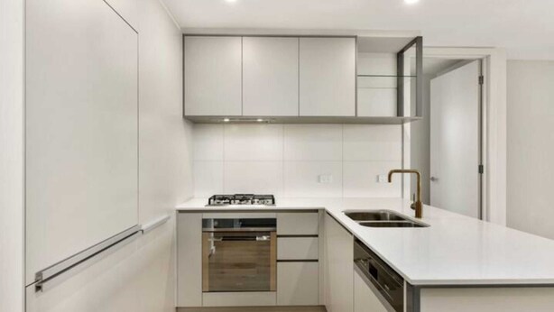Een moderne keuken met witte kastjes, een inbouwoven en een roestvrijstalen spoelbak.