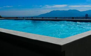 A swimming pool with a view of mountains in the background. - Infinity Pool Apartment (San Salvador)