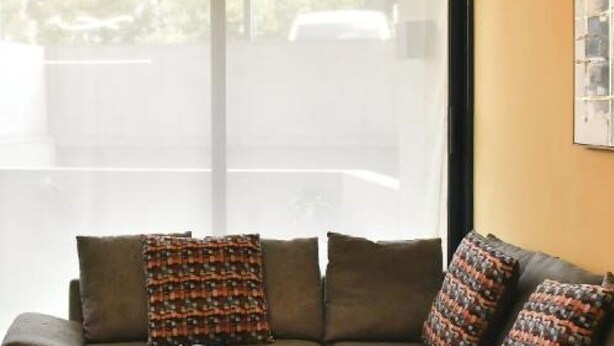 Una habitación con sofá, televisión de pantalla plana y ventana con persianas.