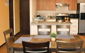 A compact kitchen with wooden cabinets, a stainless steel stove, and a refrigerator. - Infinity Pool Apartment (San Salvador)
