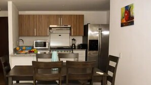 Cocina compacta con muebles de madera, microondas, estufa y refrigerador.