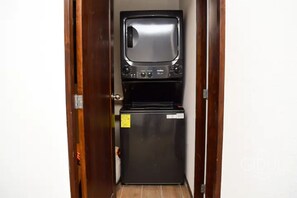Una kitchenette funcional con refrigerador y un televisor pequeño.