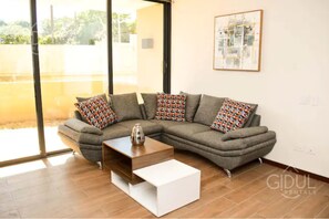 Una sala moderna con un sofá modular, una mesa de centro y un ventanal con vistas al exterior.