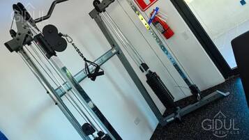 A gym with exercise equipment, a fire exit sign, and a water bottle on the wall.