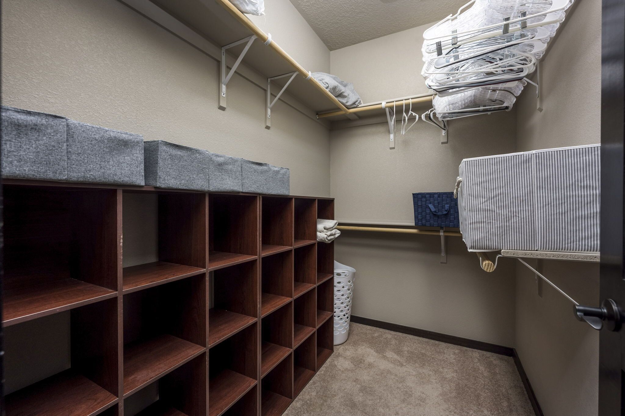 A storage closet with wooden shelves and hanging racks for clothes.