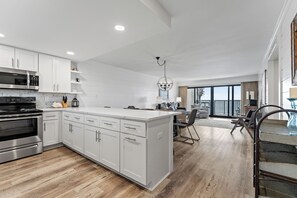 A modern kitchen with white cabinetry, stainless steel appliances, and a large island.