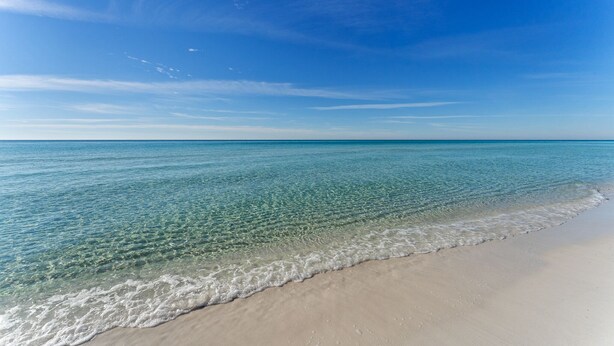 Ein Strand mit klarem Wasser und sandigem Ufer.