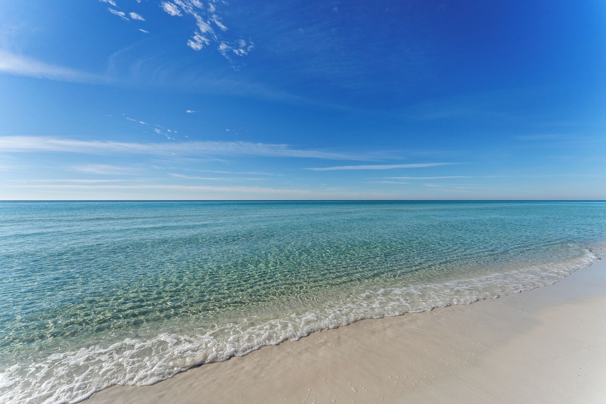 A beach with clear water and a sandy shore.