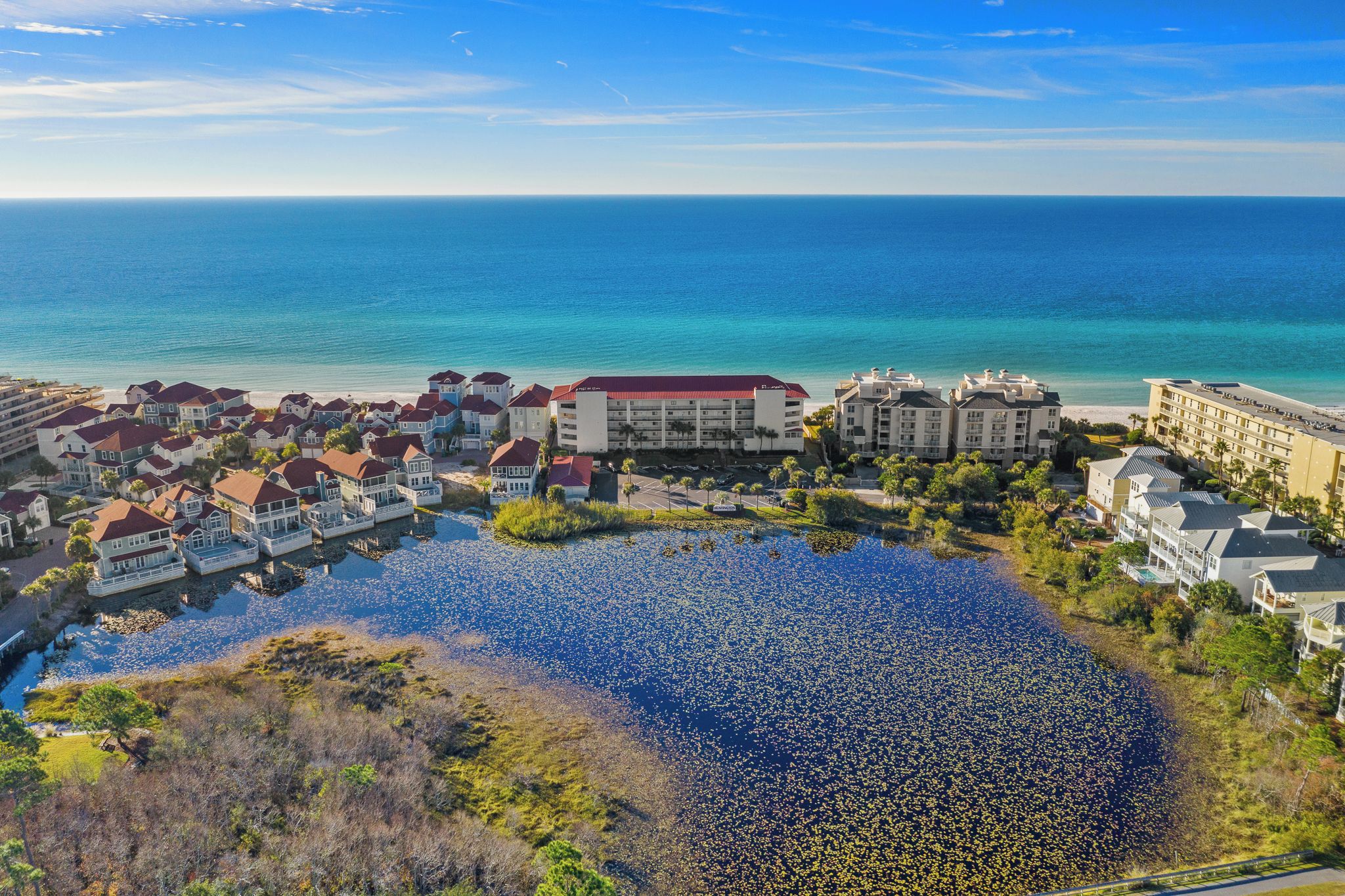 A coastal resort with multiple buildings, a large body of water, and a clear view of the ocean.
