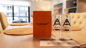 A table with a placemat, a box labeled 'wynwood', and two bottles of 'andea' water. - Soho Apartments in Miraflores by Wynwood-House (Lima)