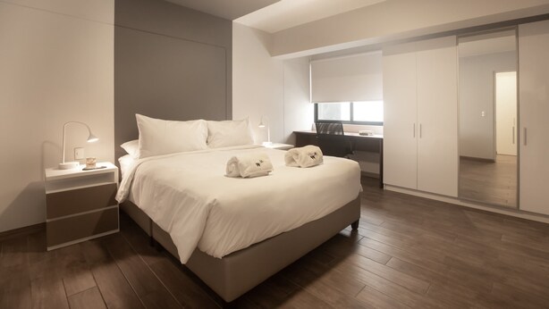 A modern bedroom with a large bed, bedside tables, a desk, and a wardrobe. - Soho Apartments in Miraflores by Wynwood-House (Lima)