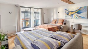 Ein modernes Schlafzimmer mit einem großen Bett, einem Schreibtisch und Blick auf die Stadt durch große Fenster.