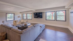 A spacious living room with a large sectional sofa, a coffee table, and a TV mounted on the wall.