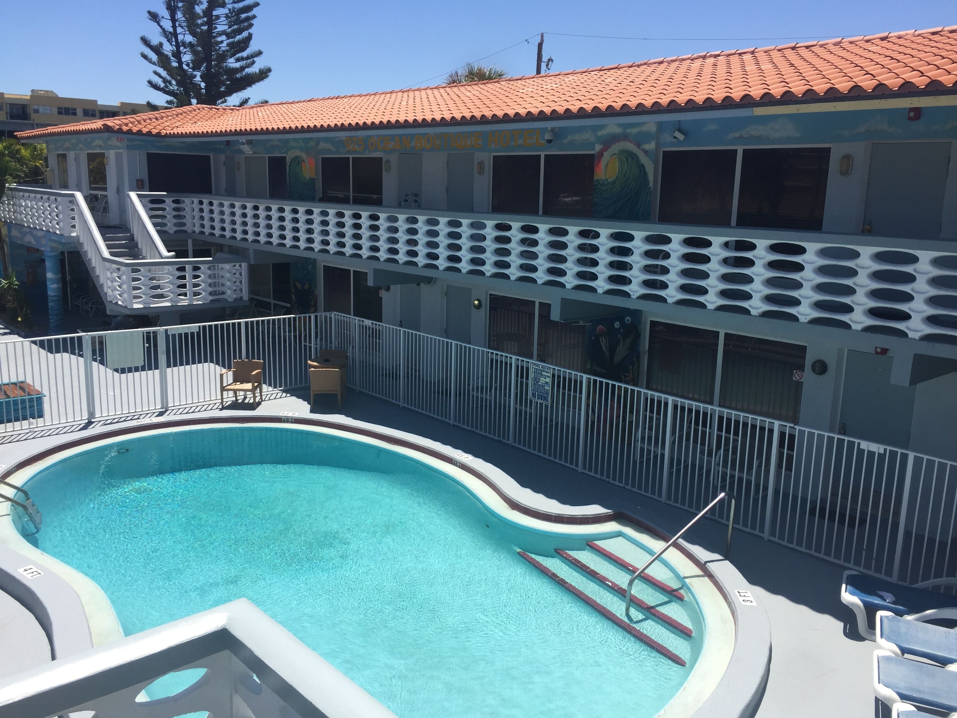 Un hôtel doté d’une piscine, d’une terrasse couverte et d’une fresque ornant le bâtiment.