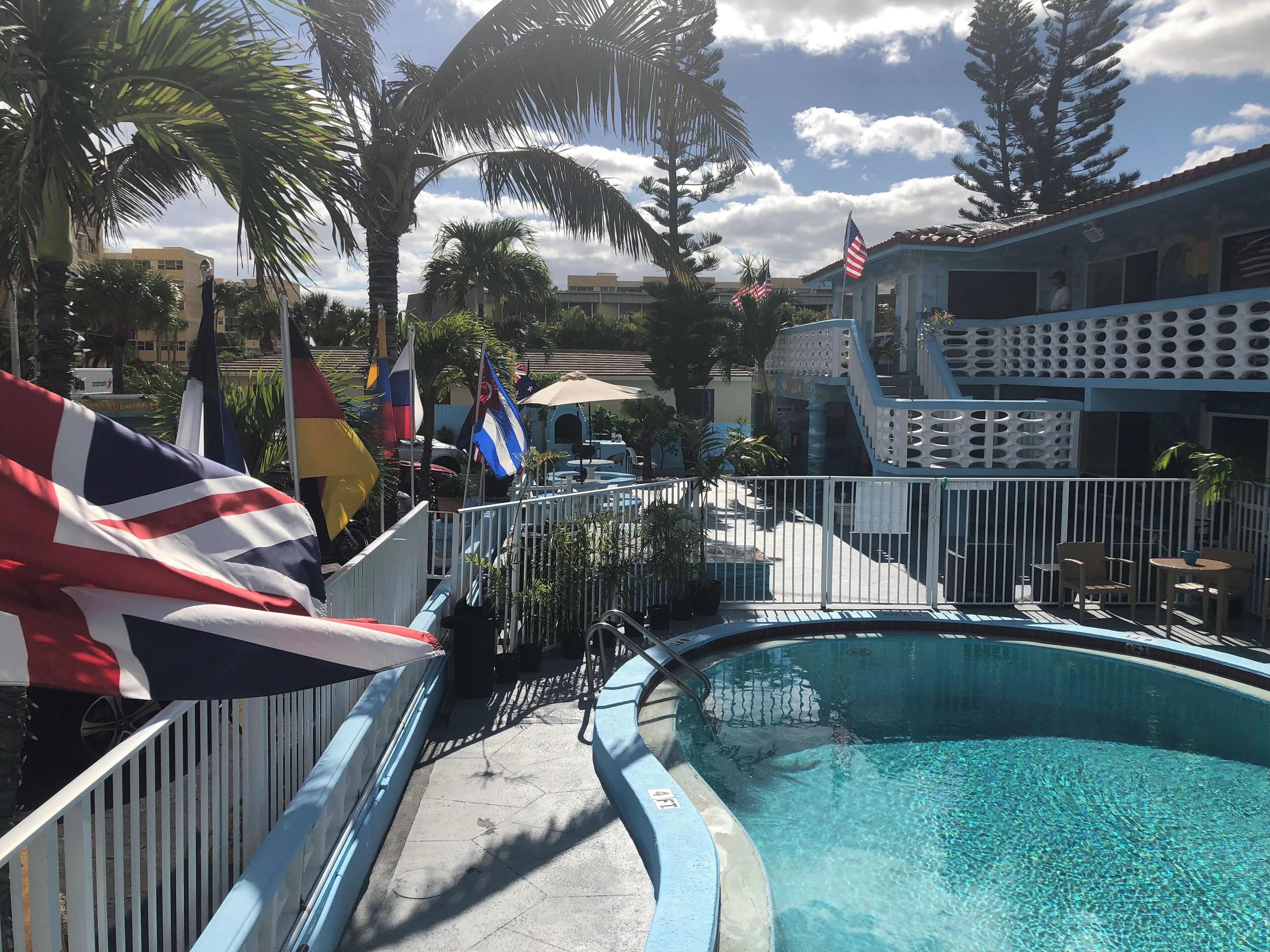 Ett poolområde med en blå pool, palmer och flaggor.