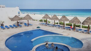 A pool area with lounge chairs and umbrellas, a smaller hot tub, and a view of the beach. - Luxury Villa at the feet of the sea In Cancun (Cancún)