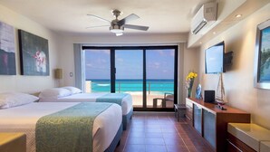 A hotel room with two beds, a balcony with a view of the ocean, a ceiling fan, and a TV. - Luxury Villa at the feet of the sea In Cancun (Cancún)