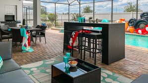 Une terrasse extérieure couverte avec une piscine, un bar et des espaces pour s’asseoir.