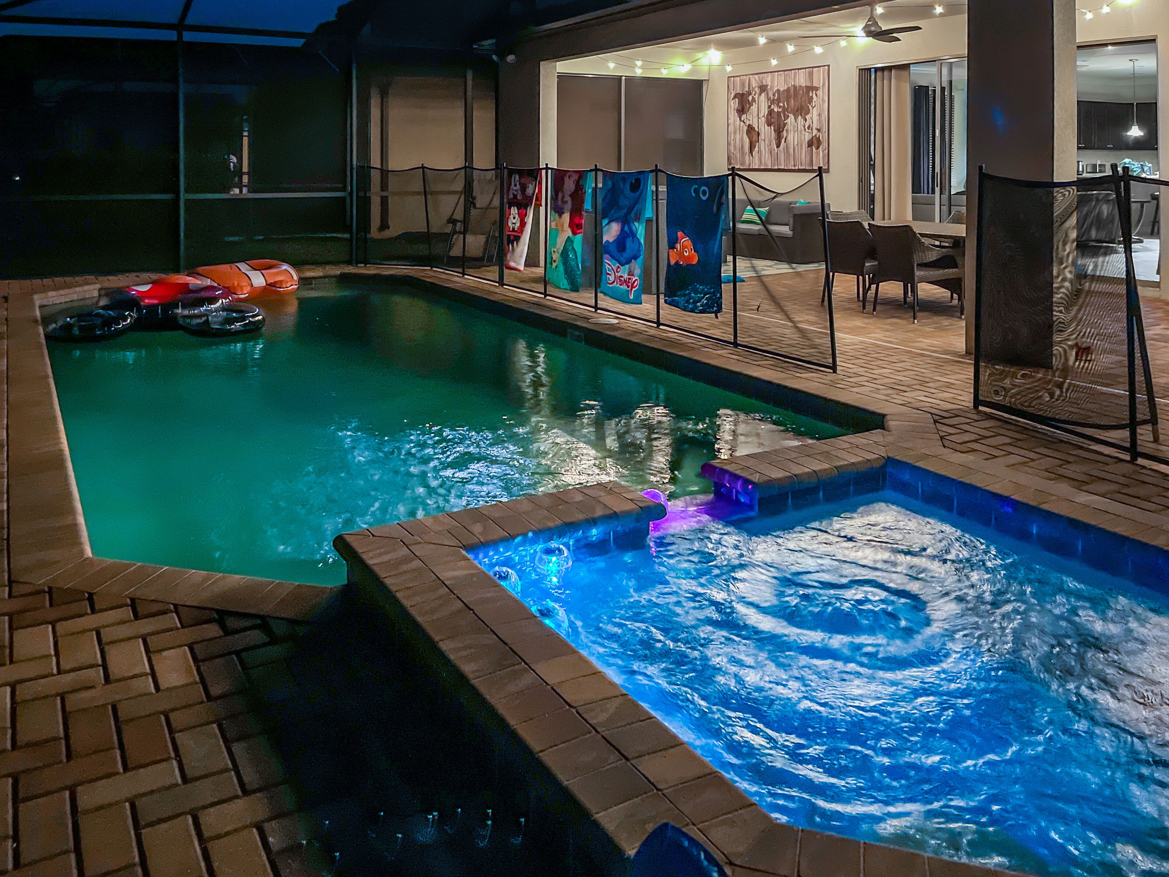 Une piscine avec un jacuzzi, entourée d’une terrasse aménagée avec des chaises et une table.