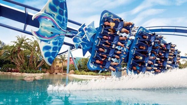 Une attraction aquatique aux couleurs bleu et blanc, avec une grande structure en forme de vague et une piscine.