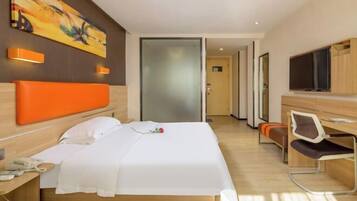 A modern hotel room with a bed, a desk, a chair, a TV, and a painting on the wall.