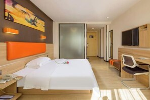 A modern hotel room with a bed, a desk, a chair, a TV, and a painting on the wall. - 7 Days Premiuml (Shenzhen Longgang Universiade Center Ailian subway station) (Shenzhen)