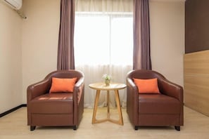 A room with two brown leather armchairs, a small wooden table with a plant, and a window with curtains. - 7 Days Premiuml (Shenzhen Longgang Universiade Center Ailian subway station) (Shenzhen)